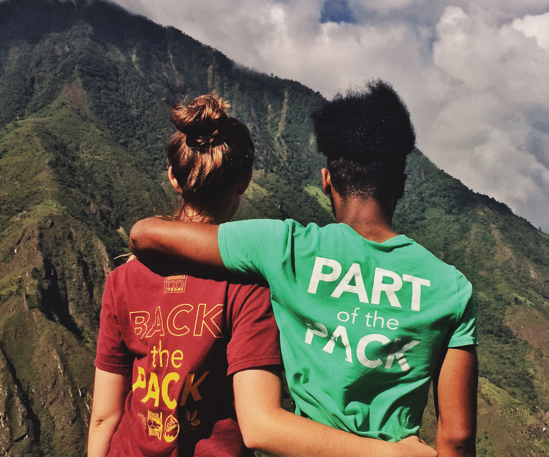 Two students hugging in view of mountain