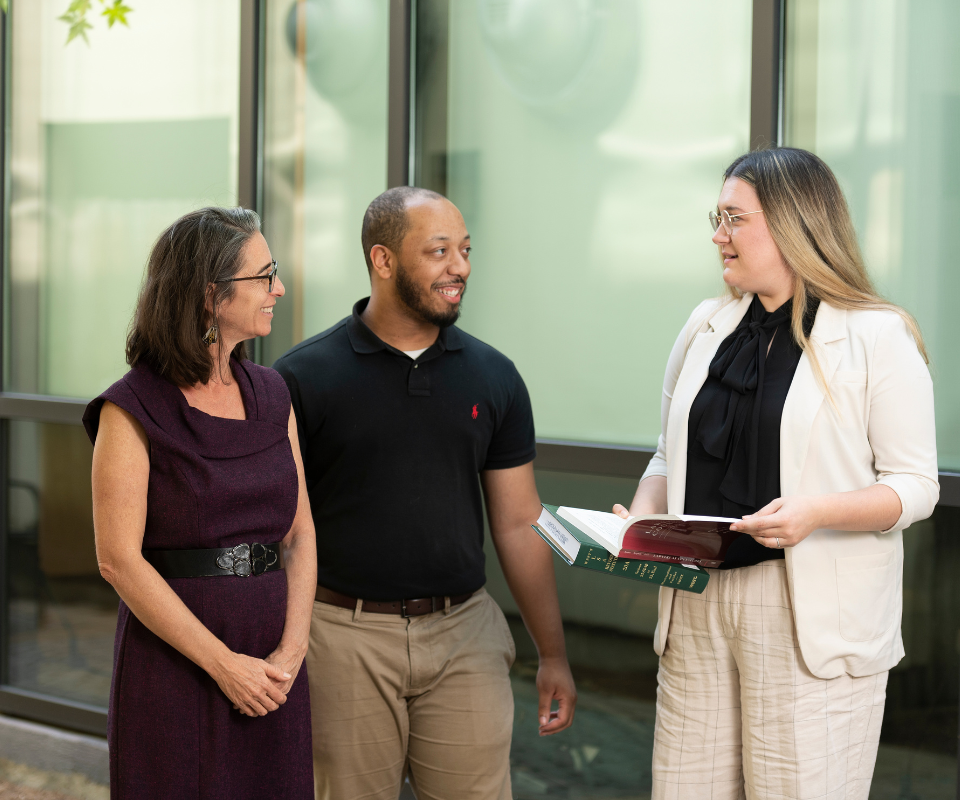 Students and a professors smile and engage in conversation.
